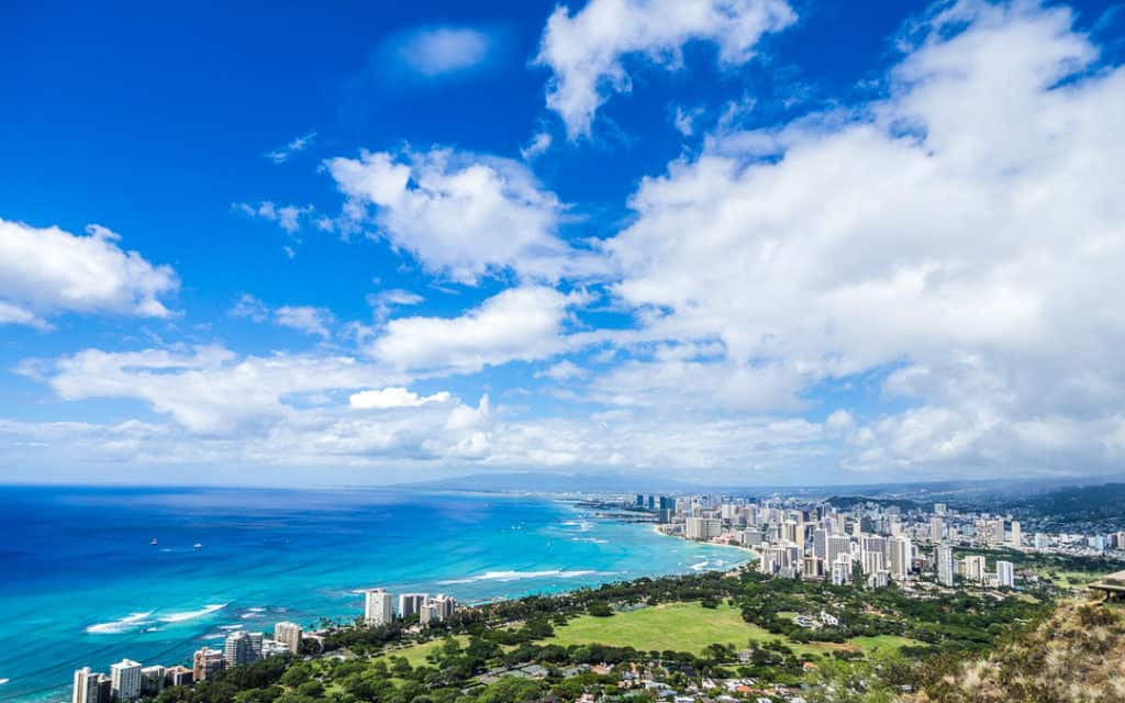 views of turquoise water beyond city and edge of beach from top of diamond head trail