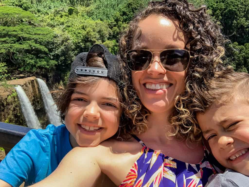 Selfie of mom wearing sunglasses with two boys in front of Wailua Falls