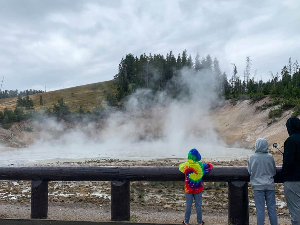 two boys and man watching bubbly muddy areas at Mud Volcano Area in Yellowstone
