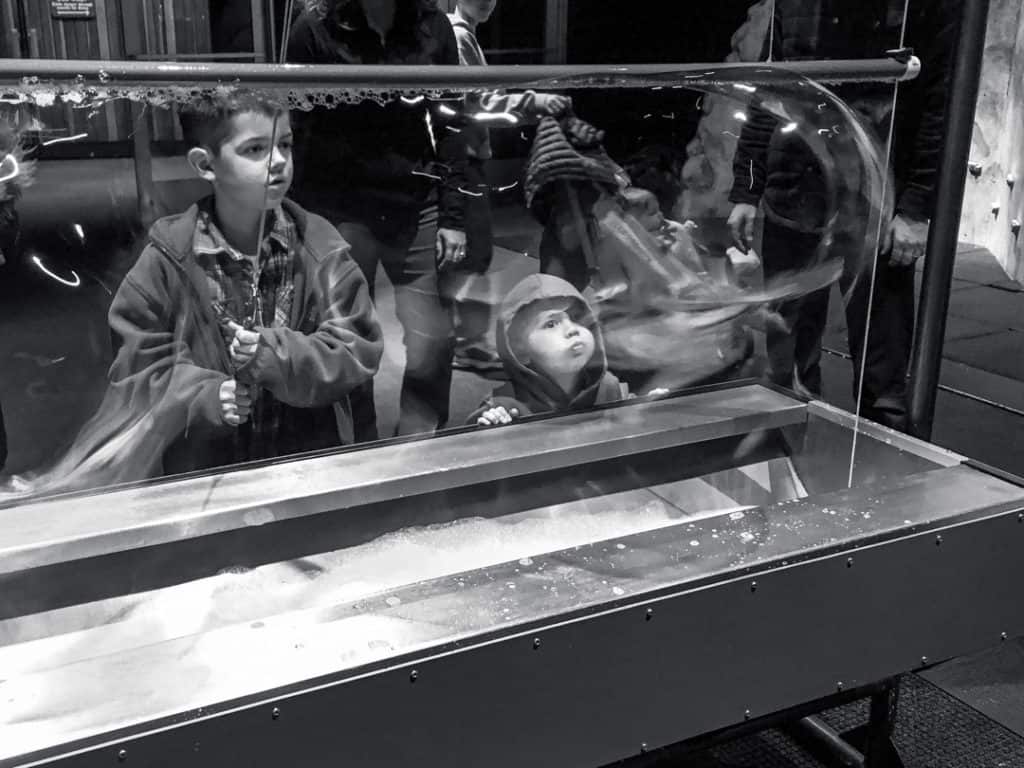 black & white image of two boys making giant bubbles at giant bubble maker at Pacific Science Center