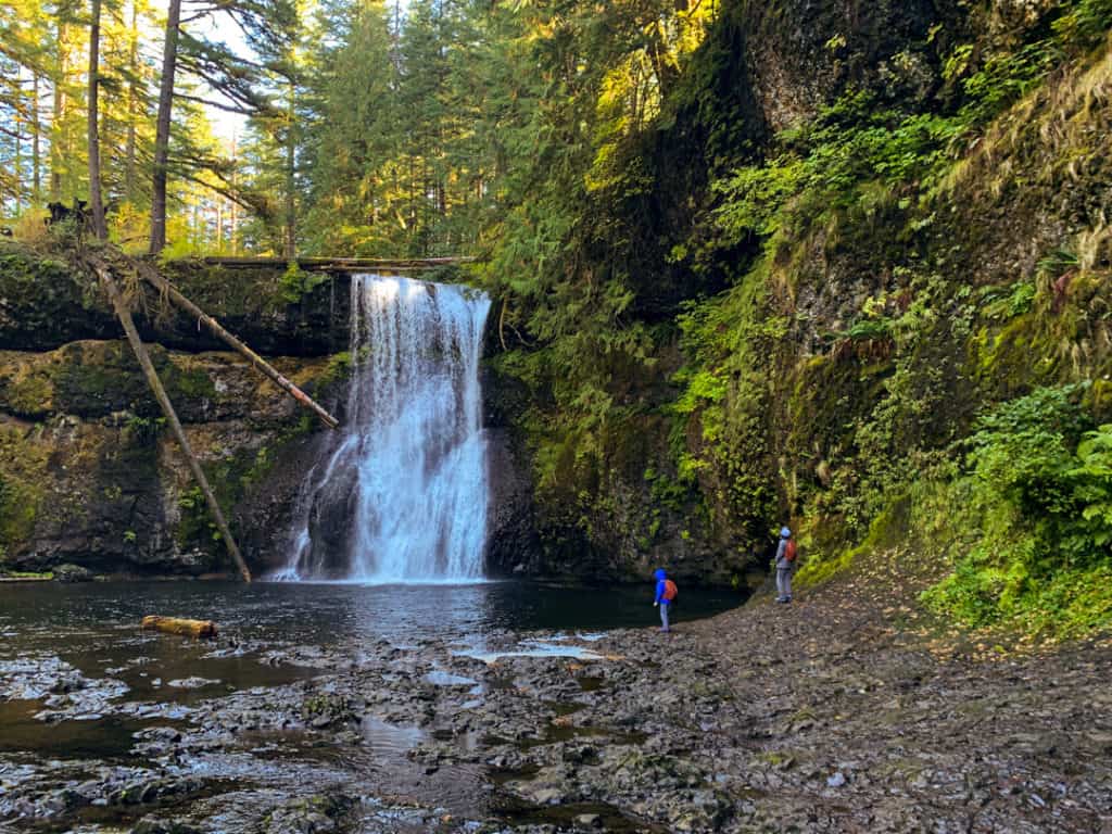 boy standing at base of waterfall during a hike at the trail of ten falls