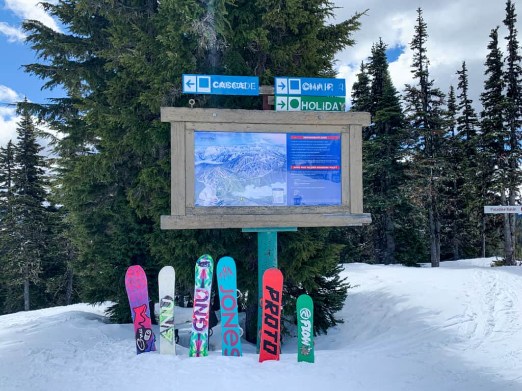 snow resort map with 6 snowboards standing up in snow in front of sign