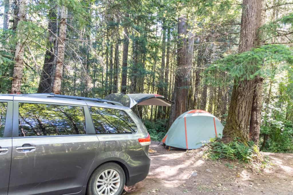 grey toyota sienna at campsite with back open to empty camping gear and tent in background