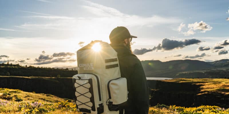 man wearing icemule boss backpack cooler at golden hour with sunburst shining through closure