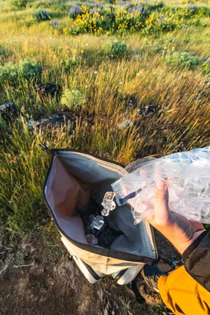 person pours ice into open top of icemule boss backpack cooler