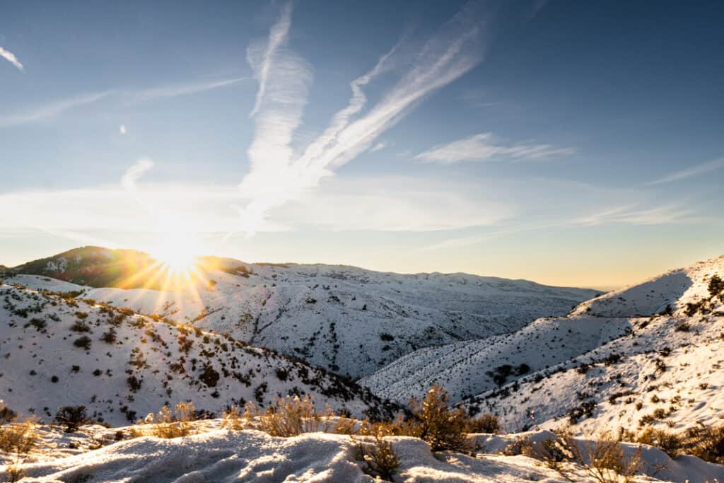 sunburst glows over top of mountain ridge at sunrise near Boise ID